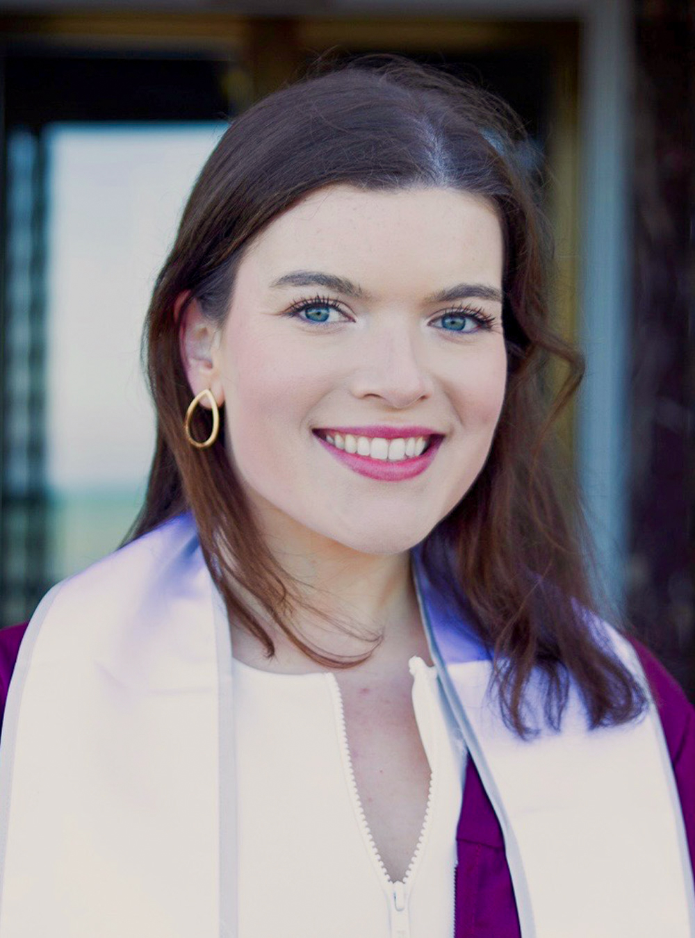 Portrait of a smiling woman wearing earrings and a light scarf outdoors