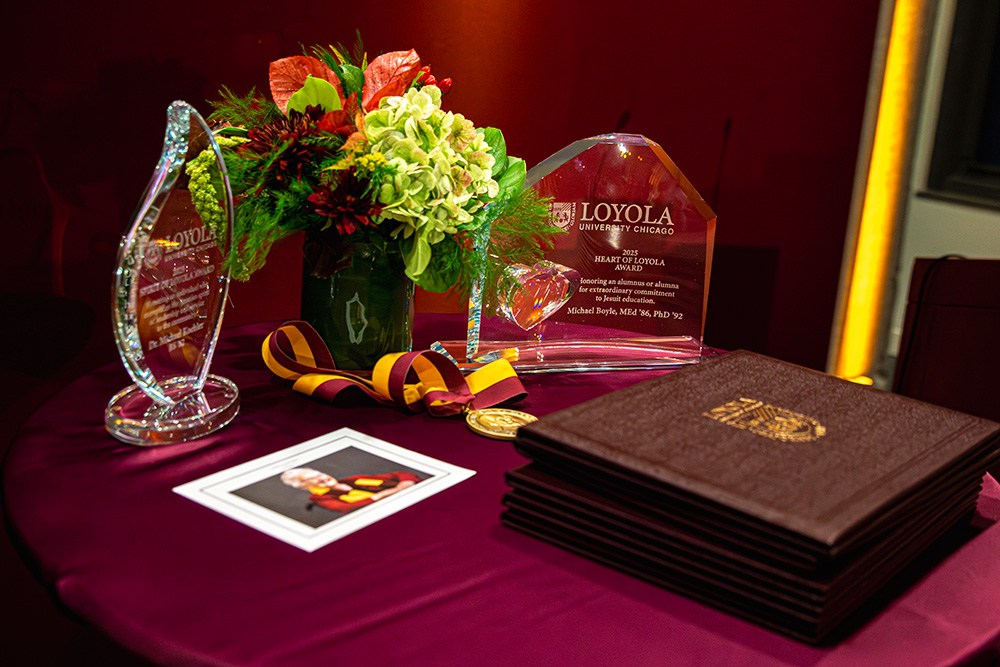 A table with the Alumni Awards presented at the ceremony arranged with flowers and a photo of Sister Jean.