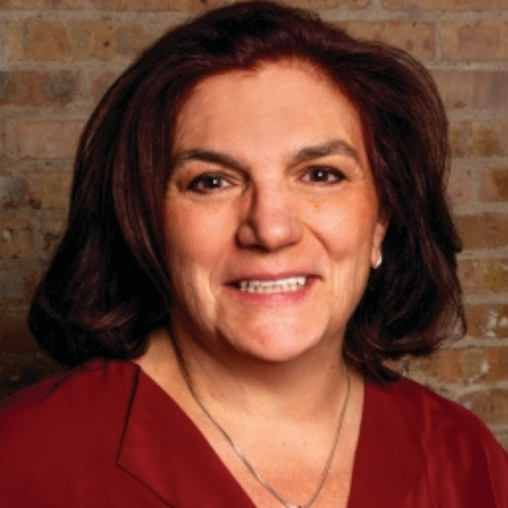 Professional headshot of a smiling woman with dark hair wearing a red top against a neutral background