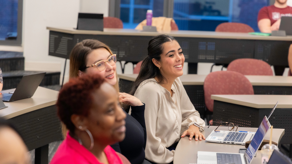Alumnae take notes on laptops at a professional development class on the Water Tower Campus.