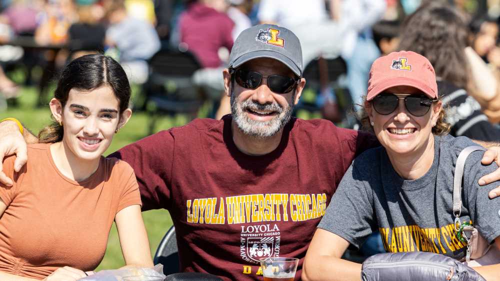 Multi-generational alumni in Loyola tee shirts gather on the quad on Lake Shore Campus for a family event.