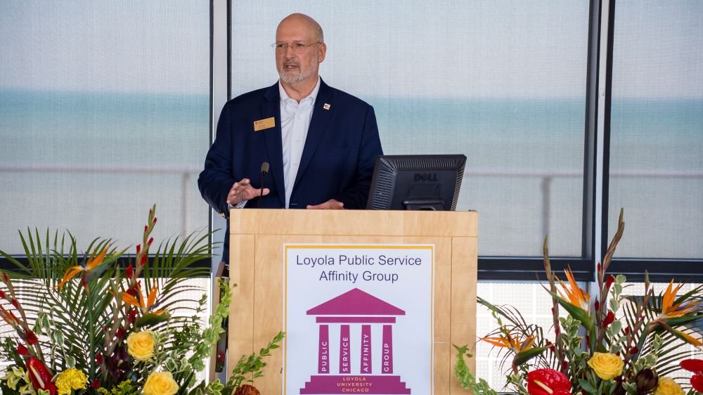 An alumnus speaks at a podium at a Public Service Affinity Group (PSAG) event.