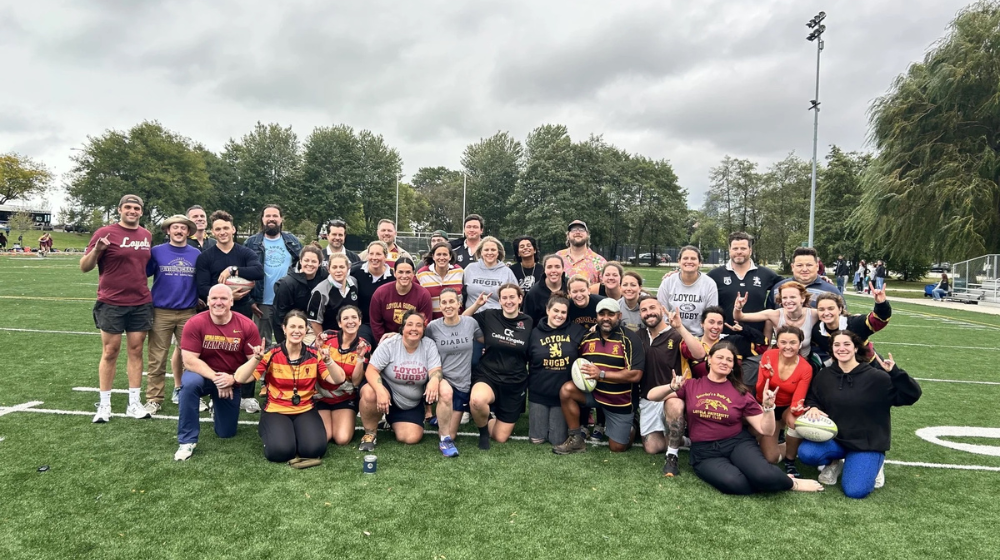 Former Loyola athletes play rugby on a field.