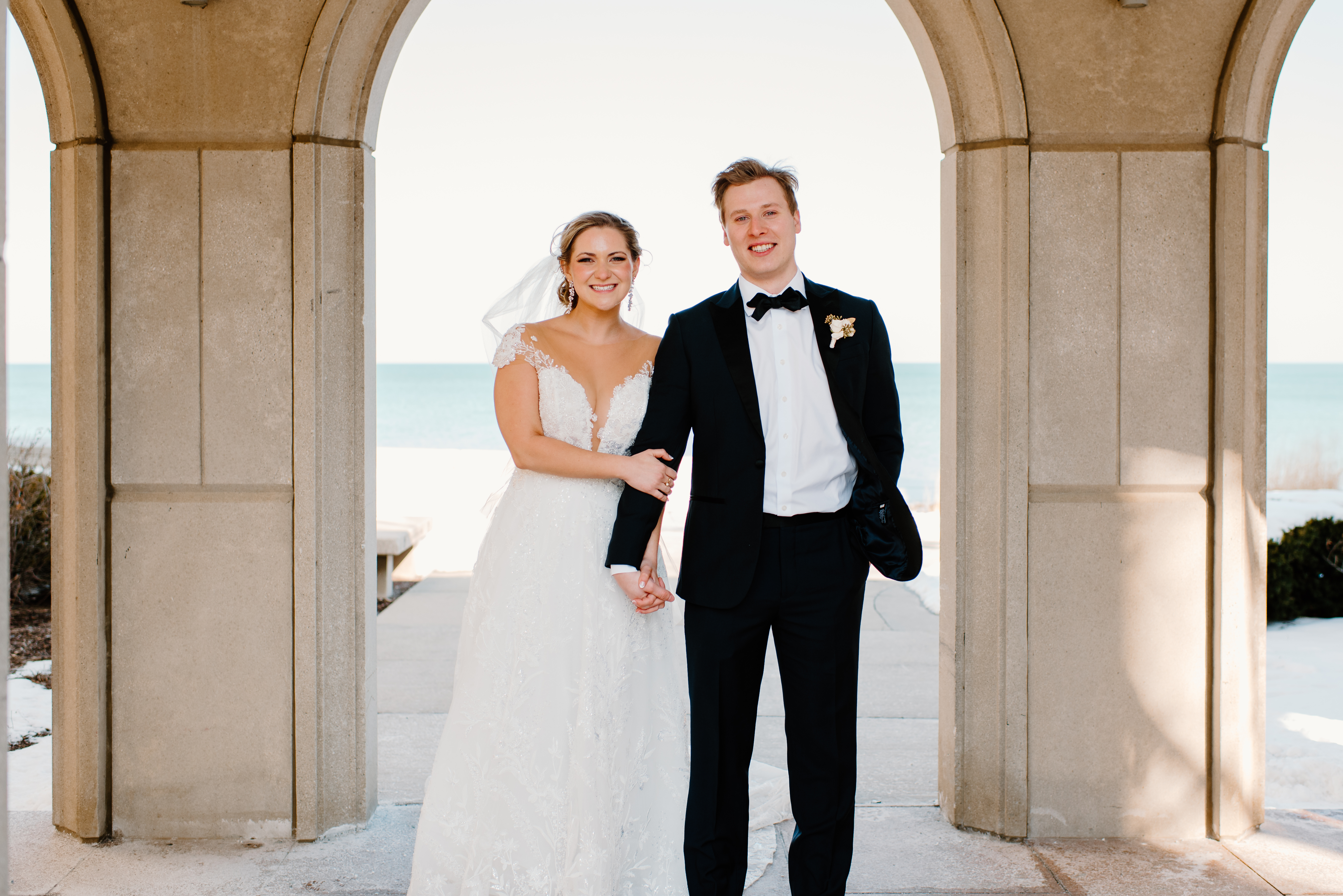 A woman in a wedding dress holding hands with a man in a tuxedo