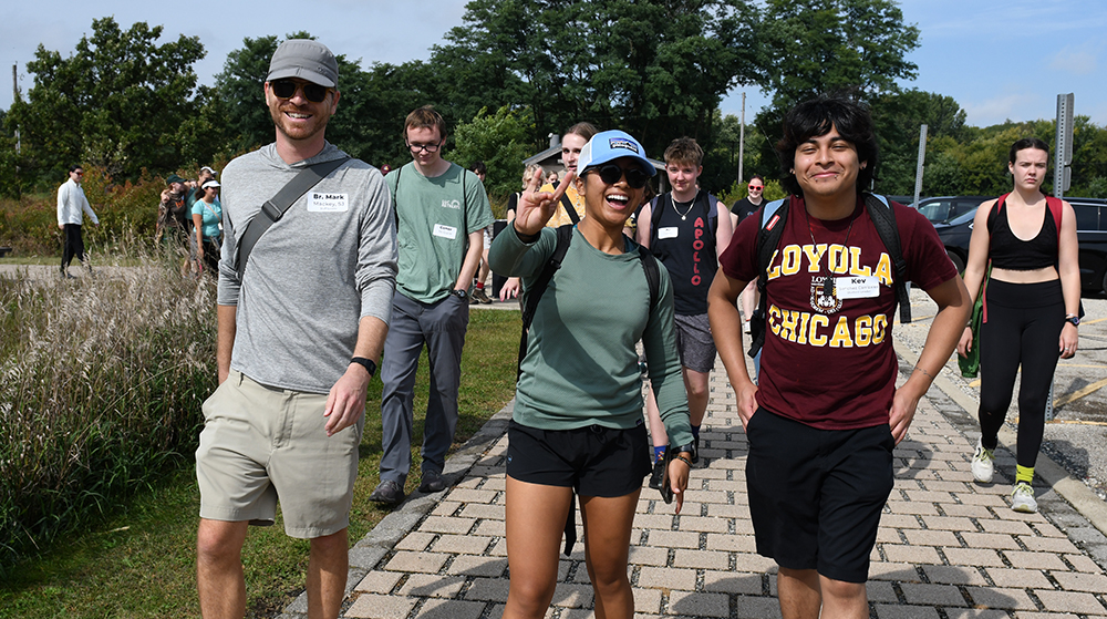 Group of students walking together on a campus path, one wearing a Loyola Chicago shirt.