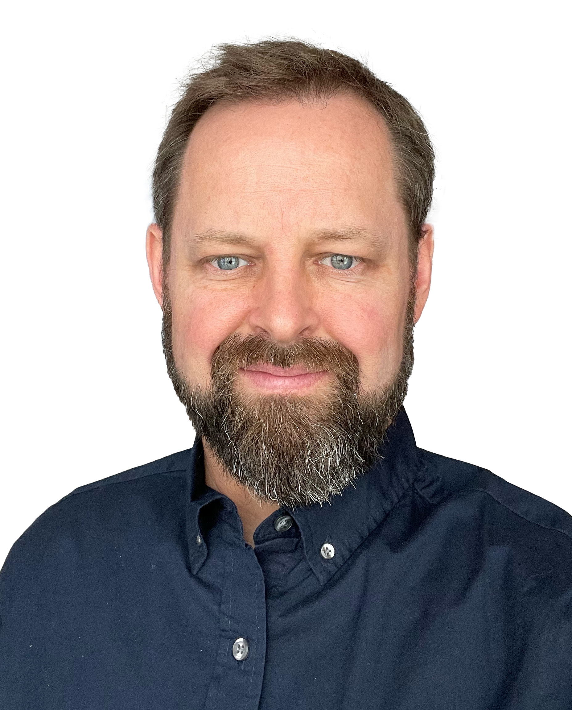 Lee Keenan wearing a dark blue button up shirt. He is smiling, standing in front of a white background.