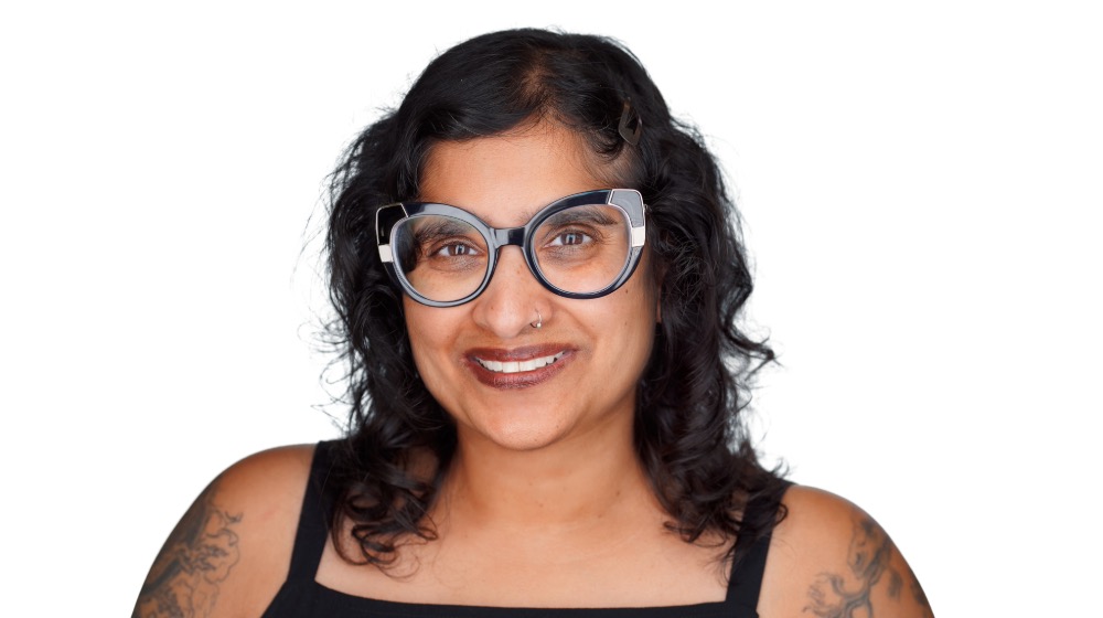 Dr. Sarita smiles standing in front of a white background.