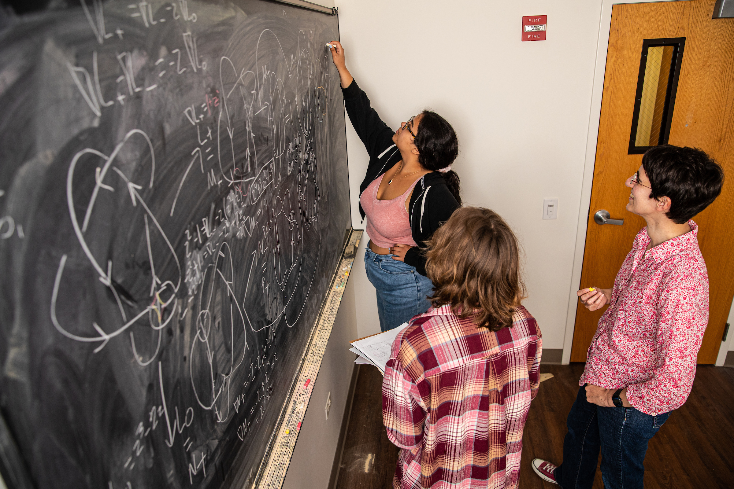 Students at chalk board working together on knot theory