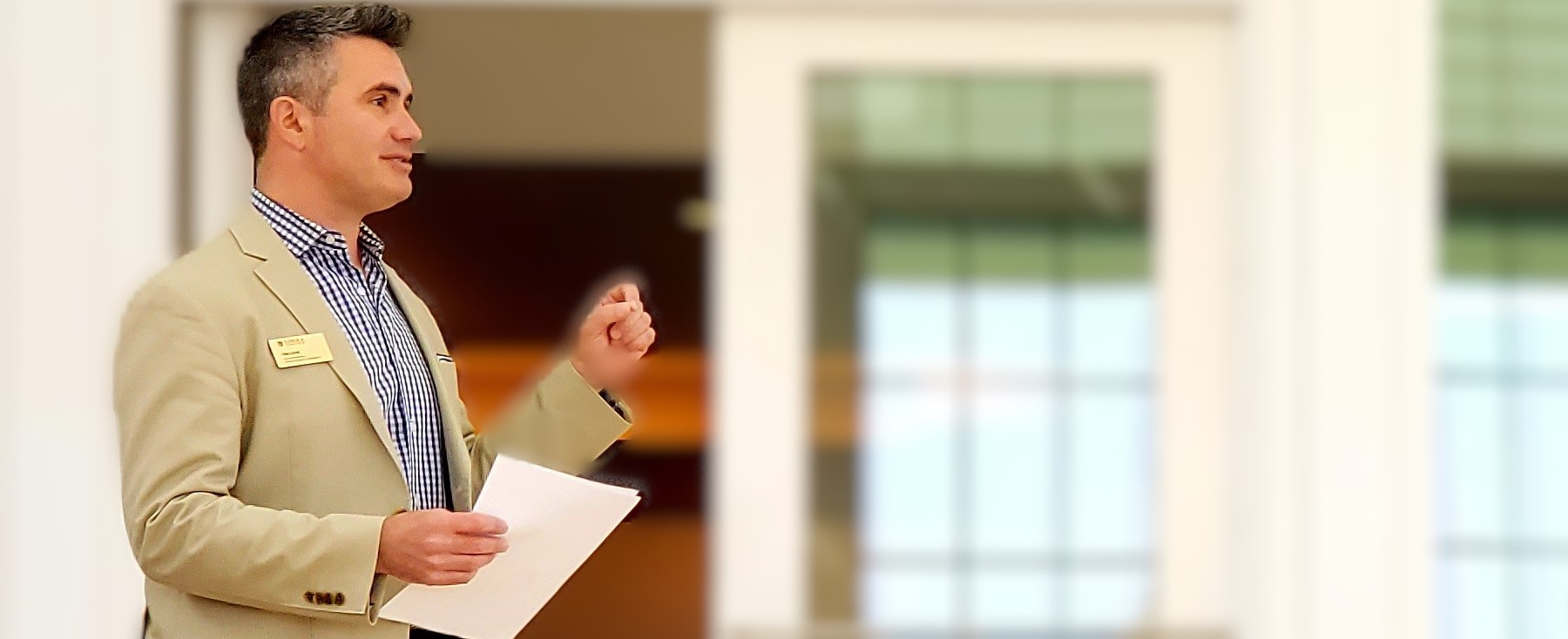 Picture of male holding papers and speaking to a group