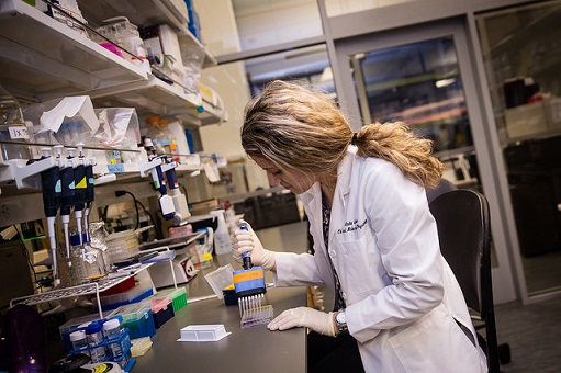 A medical student in a white lab coat performs tests in a lab.