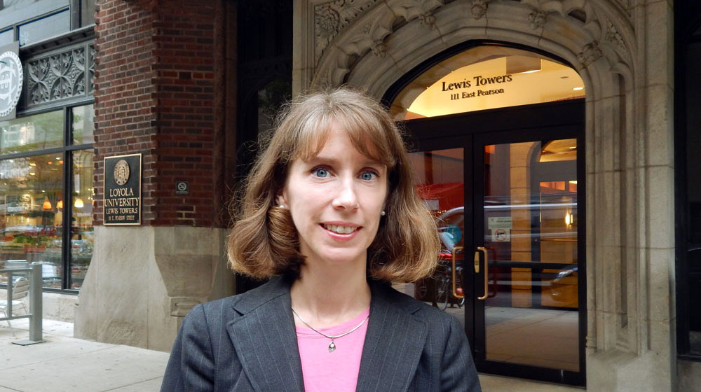 Woman standing on a city sidewalk outside the entrance to Loyola University Chicago’s Lewis Towers building