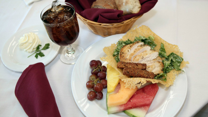 A plate of food, fresh fruit, bread, and tableware