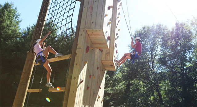 Two people climb and descend a rope hold and climbing wall