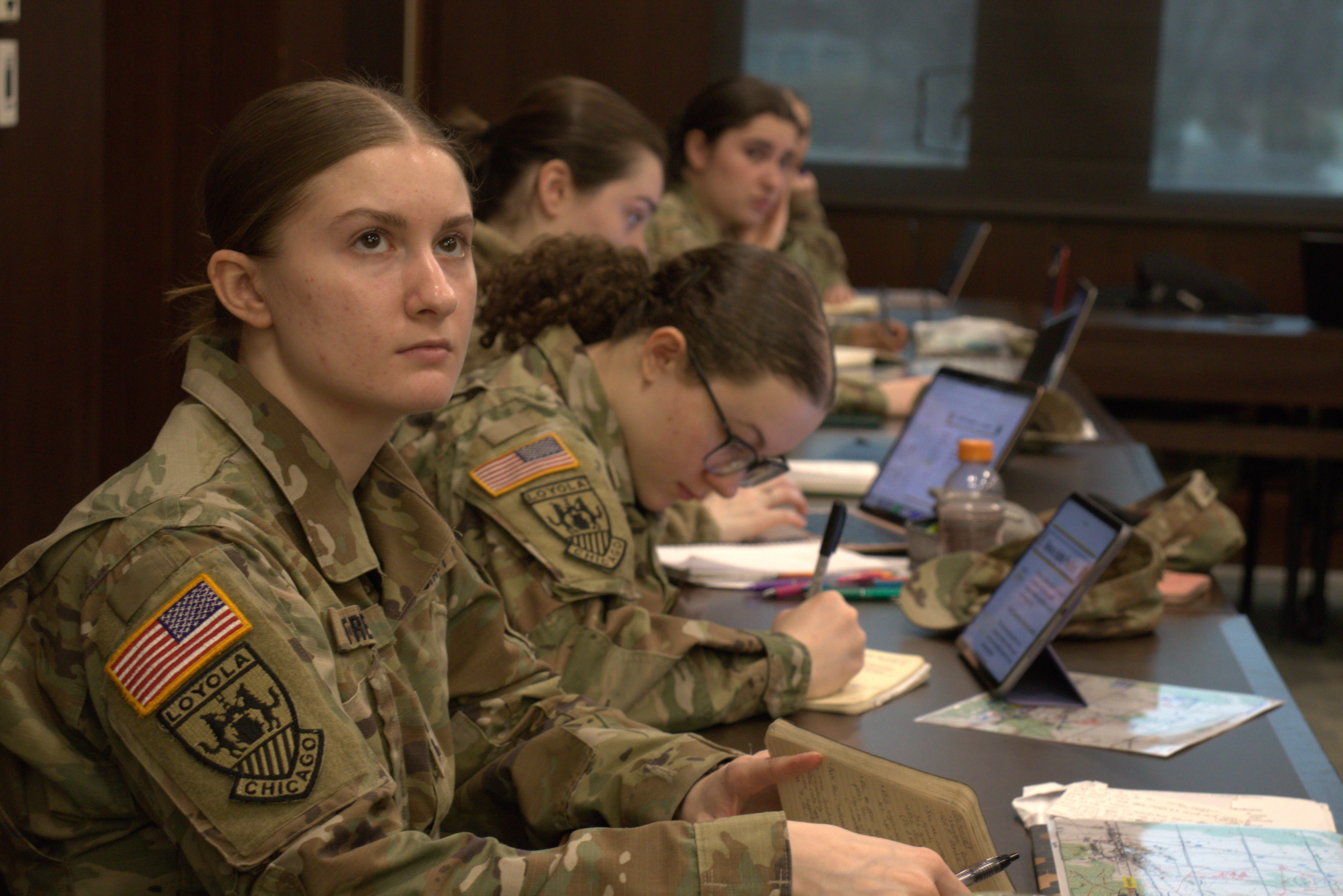 A Loyola University Chicago ROTC student listening to a lecture in a classroom with other students