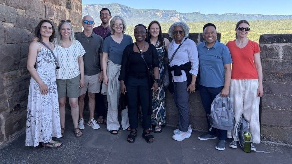 Ten Loyola staff and faculty members posing for a picture in front of a mountain