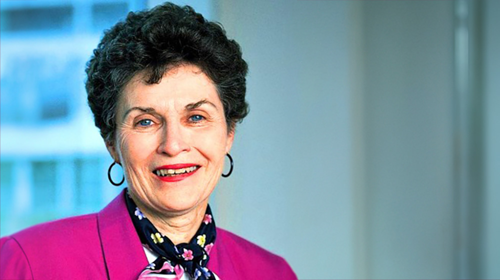 Barbara Brodie smiling while standing near an office building window