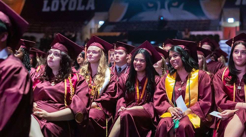 Graduates in maroon caps and gowns sit and listen during the May 2025 Commencement ceremony in Gentile Arena