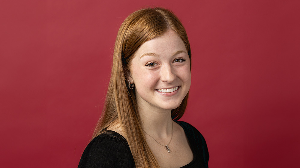 President's Medallion Recipient Grace Nelson smiling in front of a maroon background