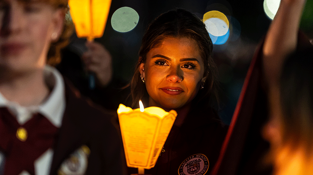 Nikolina Vujcic, a Loyola Nursing student, smiles and holds a lit candle during a nighttime procession in Lourdes, France