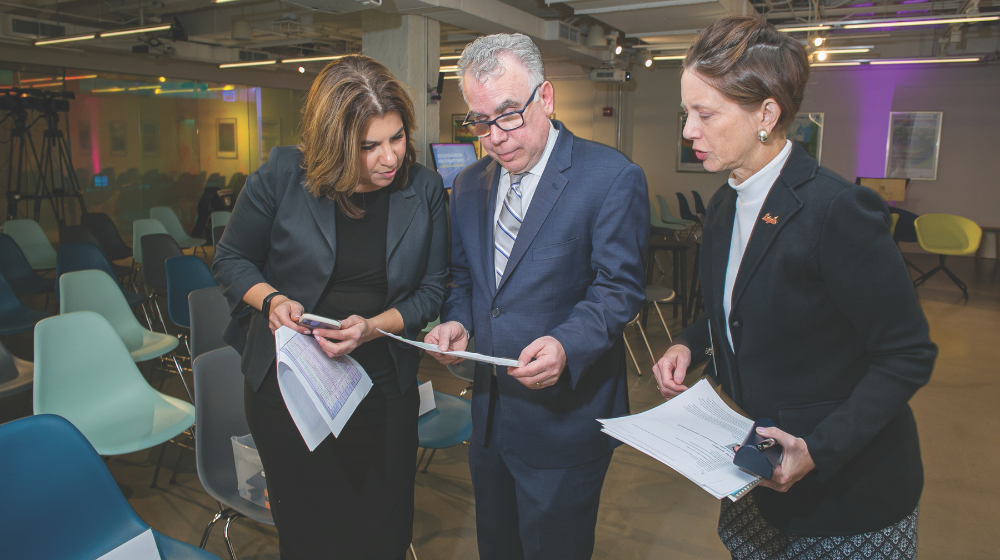 Three people gathered reading off a sheet of paper