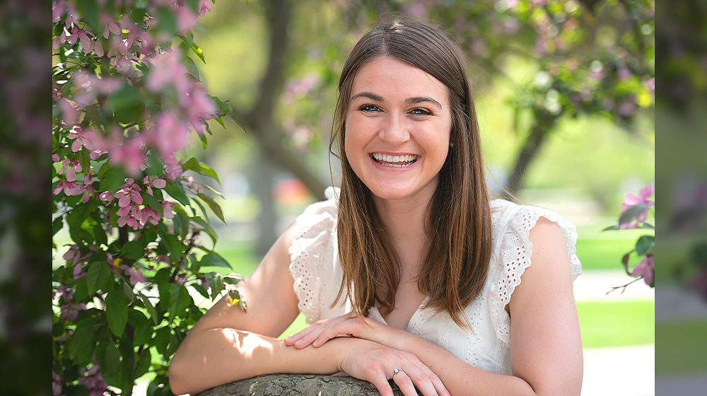 Loyola University Chicago Political Science PHD Student Ashley Grace Burkholder in between a a pink floral tree