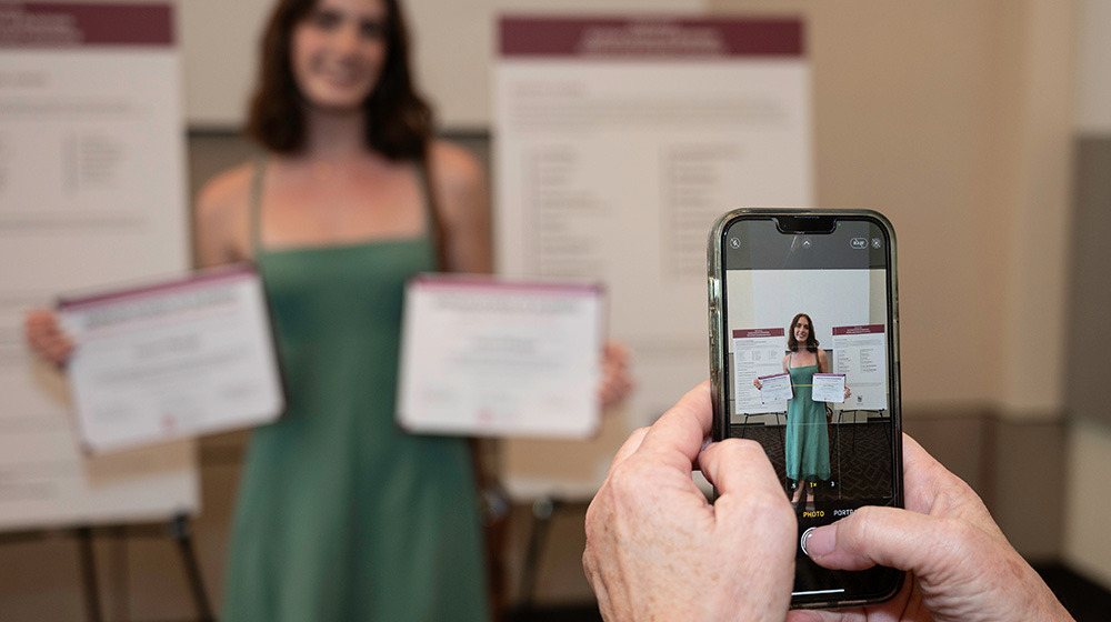 A student showing off awards from the 73rd honors and awards ceremony