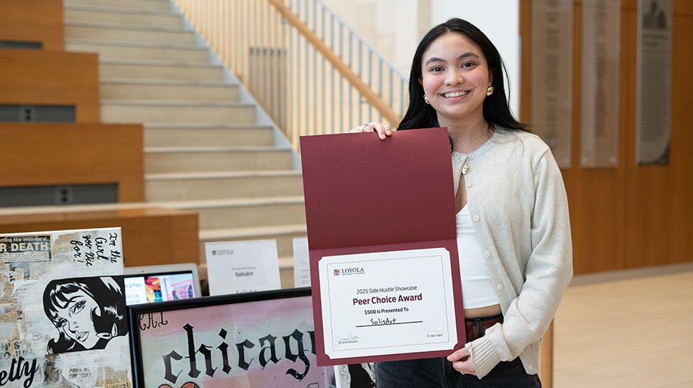Emily Narsolis holds her Peer Choice Award in front of her art