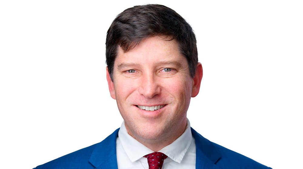 Headshot of Peter Norlander in a blue suit and red tie