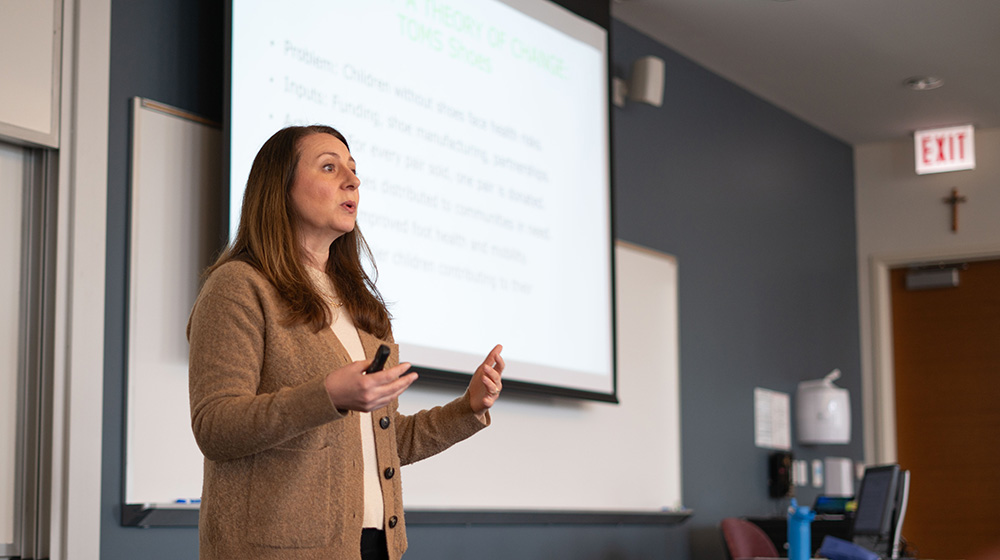 April Lane Schuster leads a lecture in her classroom in front of a projector