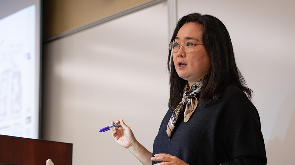 Hae Mi Choi teaching in a classroom with a whiteboard in the background