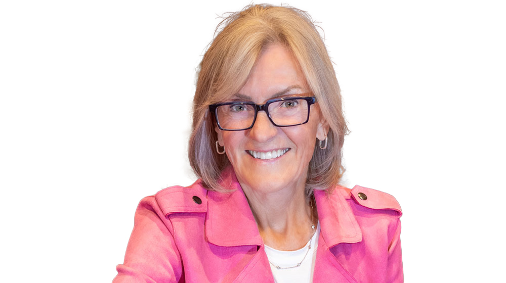Headshot of Linda Stroh sitting in an office wearing a pink jacket