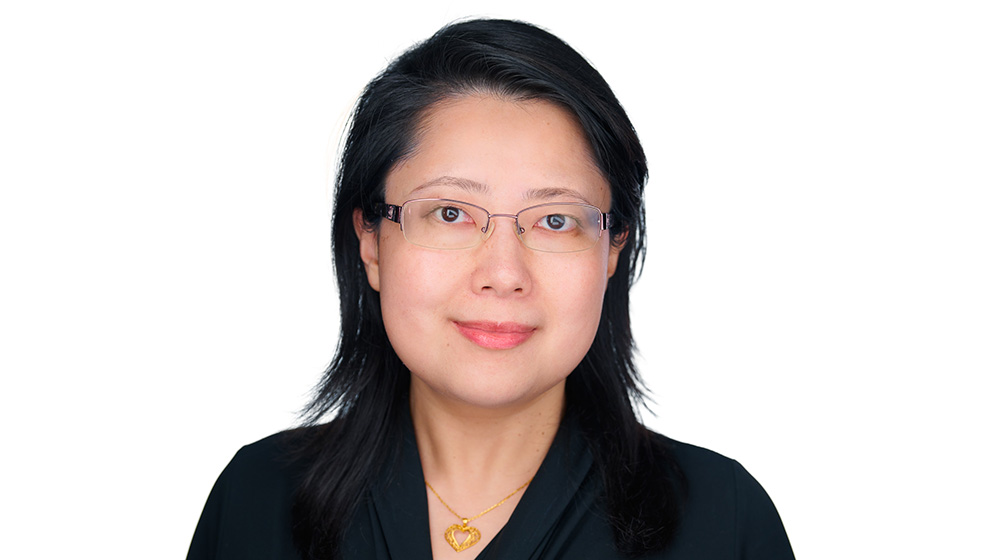 Quinlan School of Business faculty member wearing glasses and a black blouse, smiling in a professional headshot against a light background.