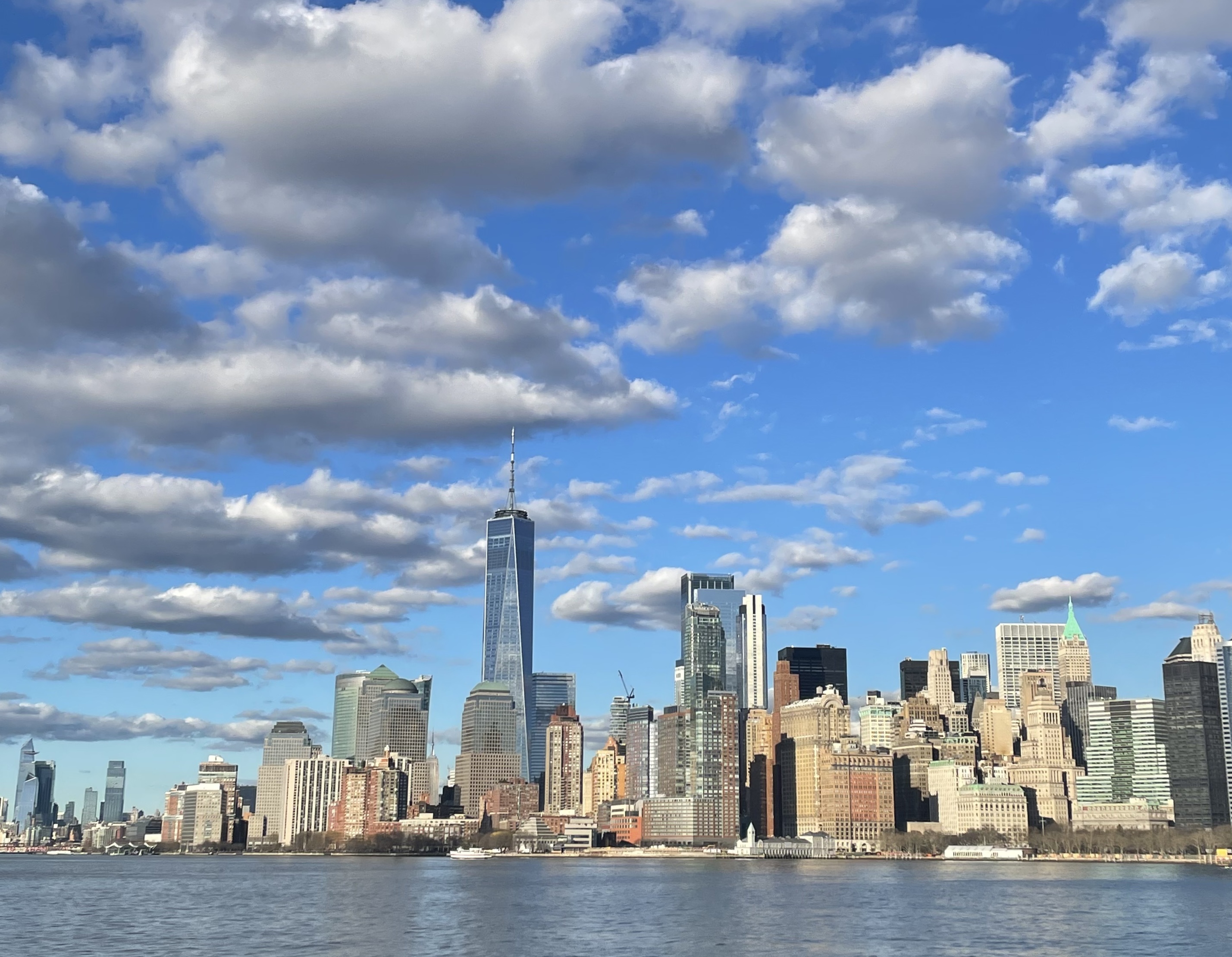 The skyline of New York City among clouds and blue sky.