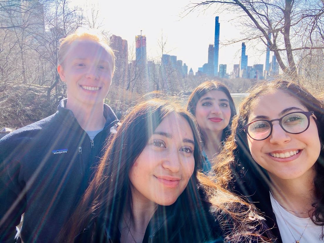 Four Quinlan Ramble students snap a photo with trees and the NYC skyline in the distance.