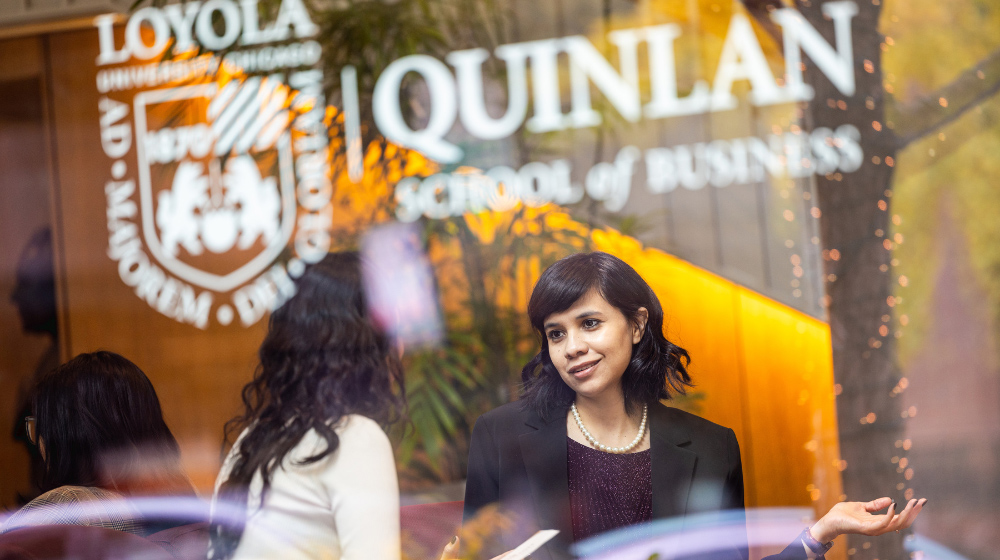 Two alumni sit in the window of the Baumhart Center