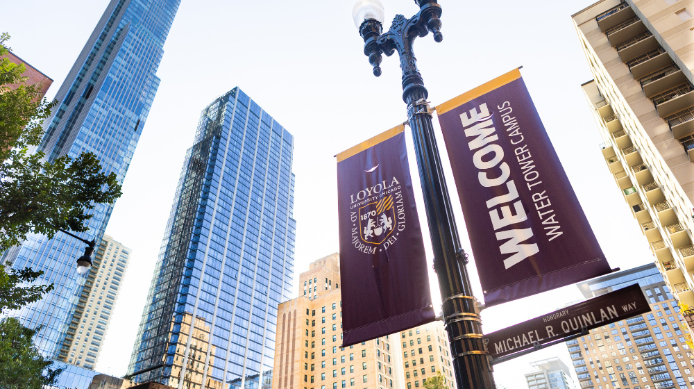 Maroon and gold Loyola University Chicago banners against a backdrop of the Chicago skyline