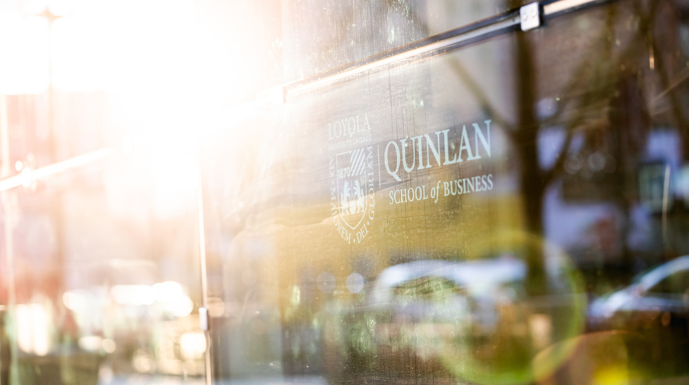 Sunlight reflects off of a window of Quinlan School of Business building