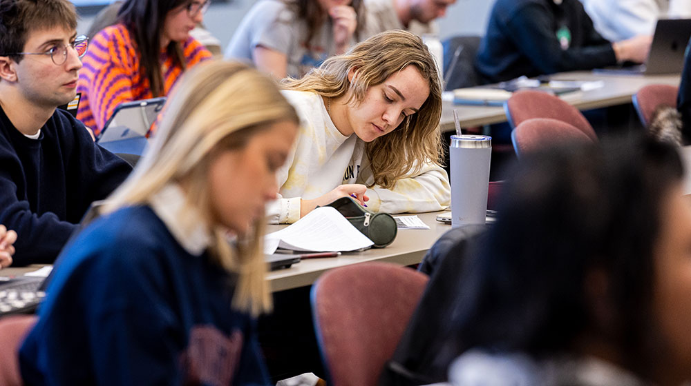 Students in a class run by Abraham Singer. One woman in the center of the class is writing notes.