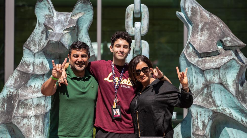 Image of parents with their son with two large wolf statues behind them