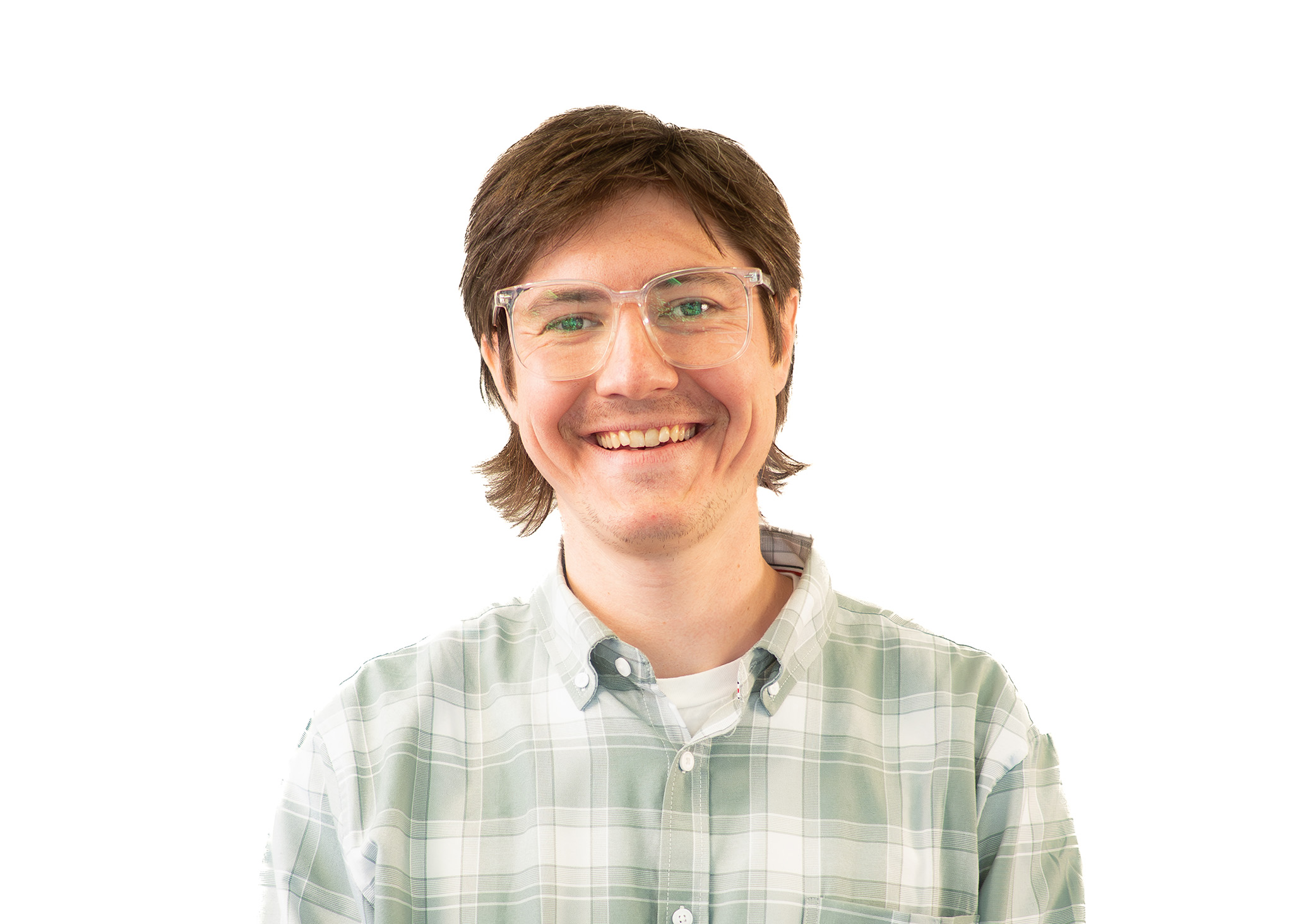 Headshot of a person with short hair and clear-framed glasses smiling, wearing a plaid shirt against a light background