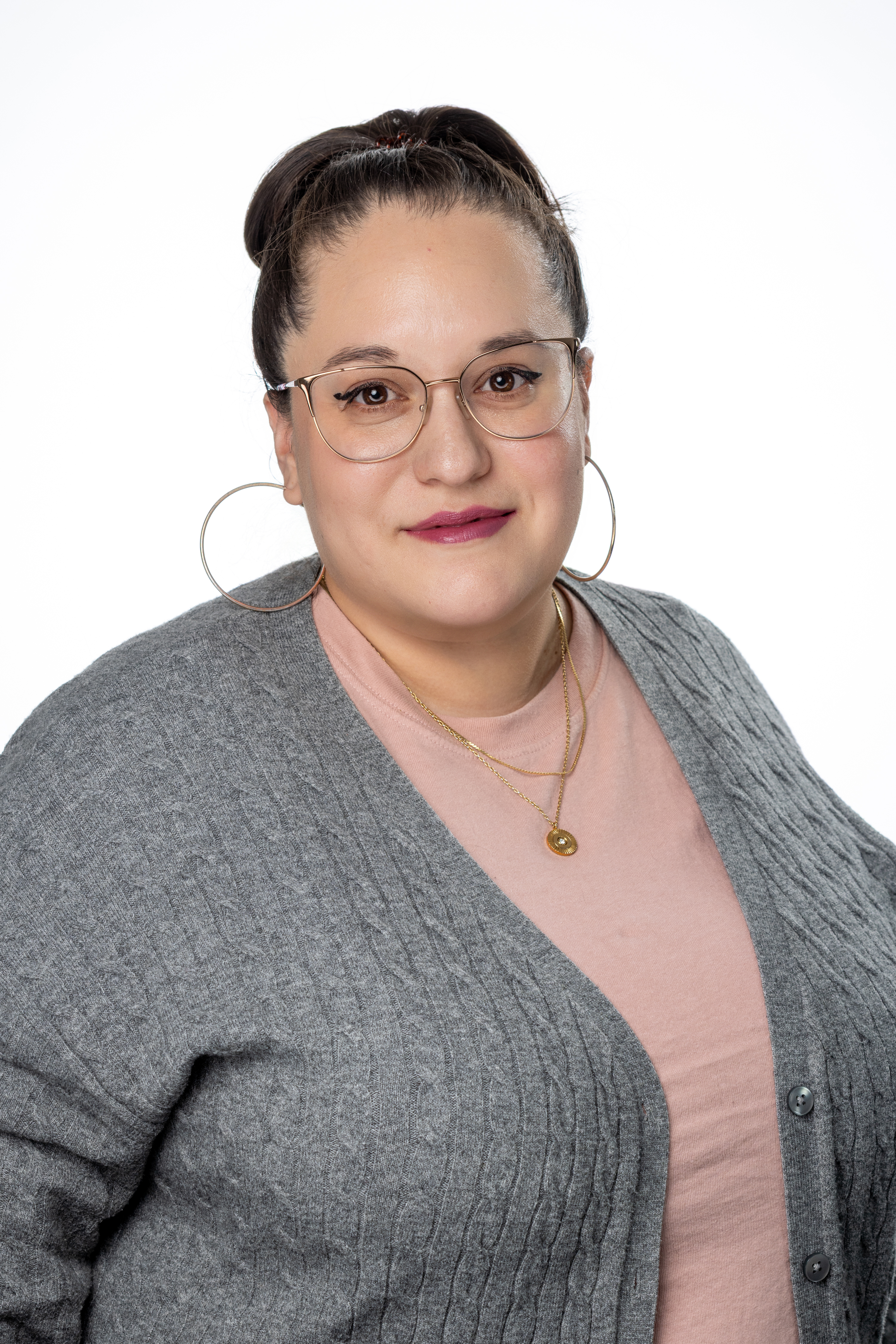 Gabriela Guardiola, Office Coordinator for Academic Affairs, wearing glasses, a pink top, and a gray cardigan, smiling against a light background.