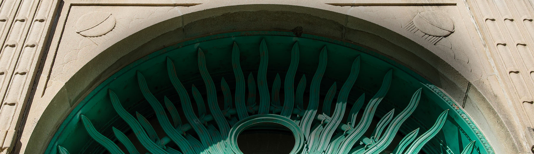 Sunlight rakes across the arc of the bright, patina, teal rays above the Cudahy 