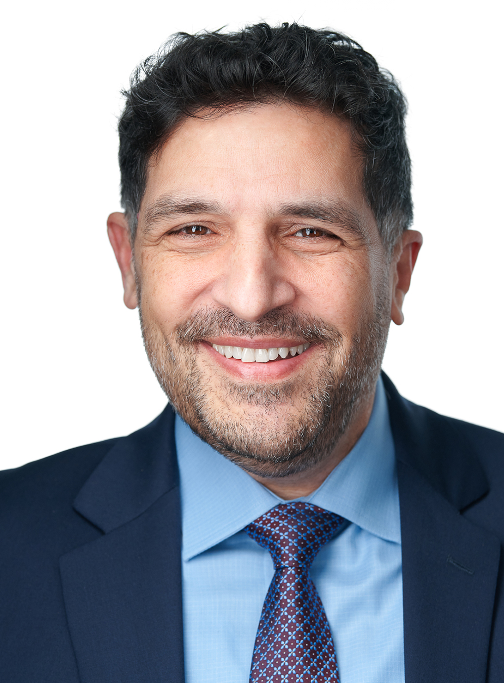Smiling man in a suit and tie against a plain background.