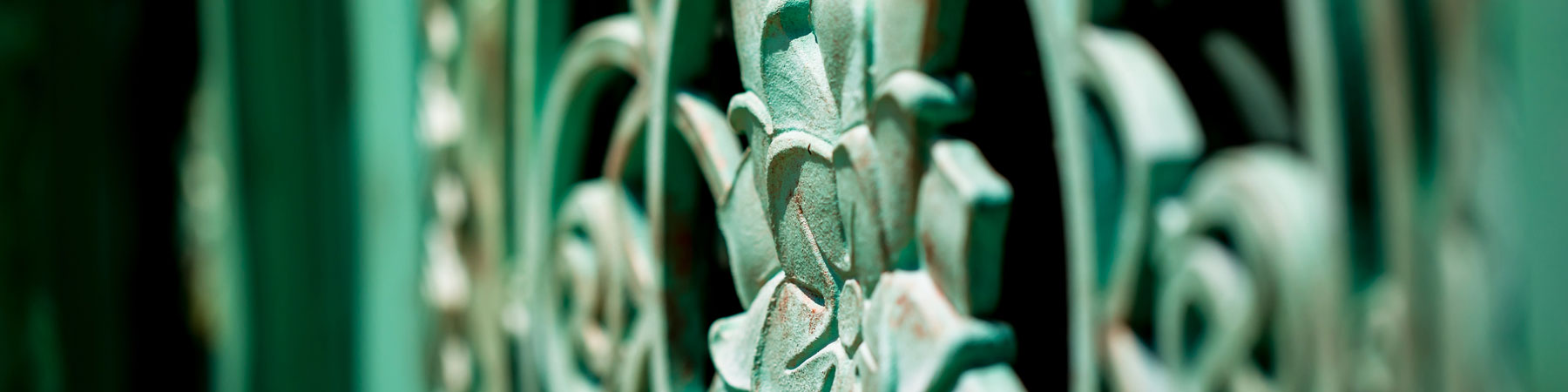 Close-up of ornate green metal gate with decorative scrollwork