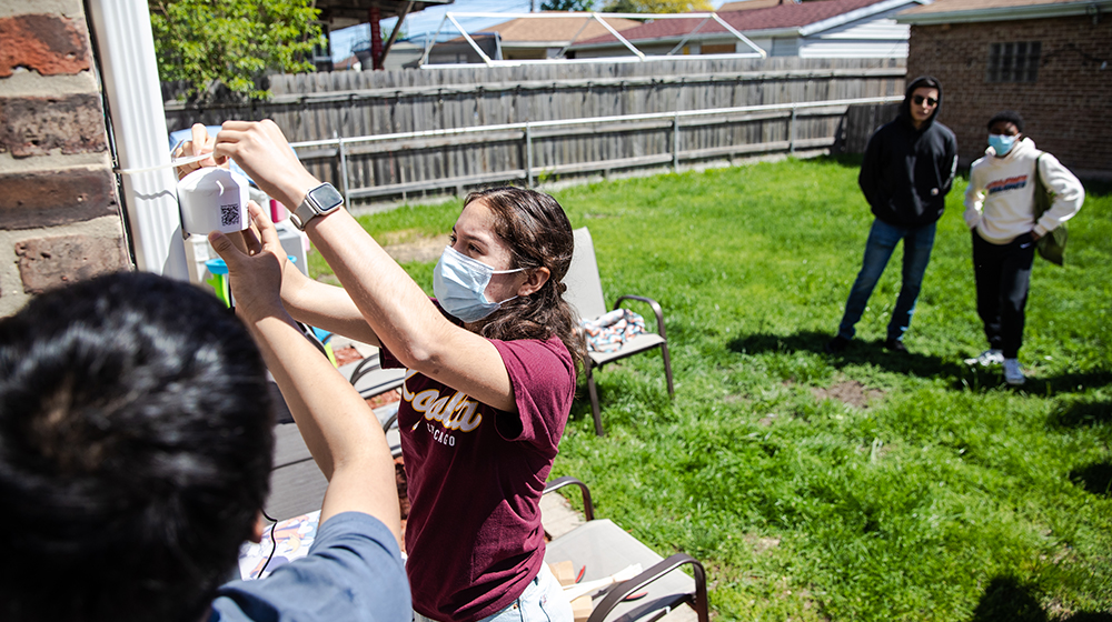 student installing an air quality monitor in a backyard