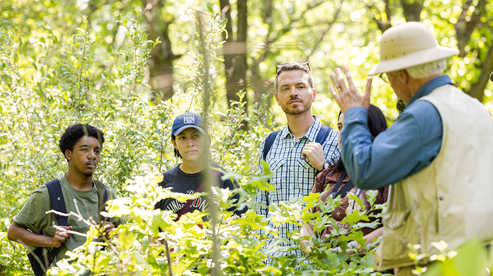 Students and instructors talking on a trail in the woods