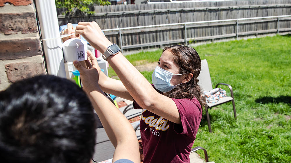 student installing and air quality monitor in a Chicago backyard