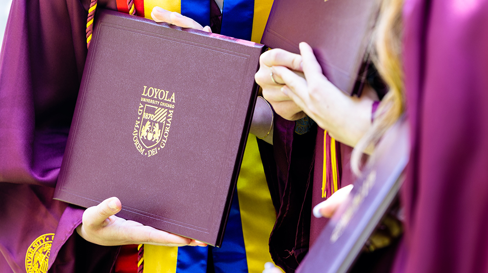hands holding a Loyola diploma
