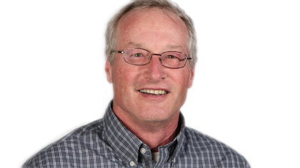 Man wearing glasses smiling against a plain background