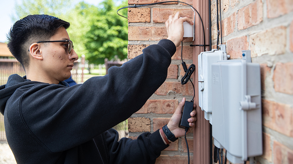 Student installing an air quality monitoring device